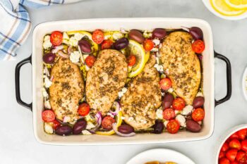 overhead view of baked greek chicken in a rectangular baking dish.