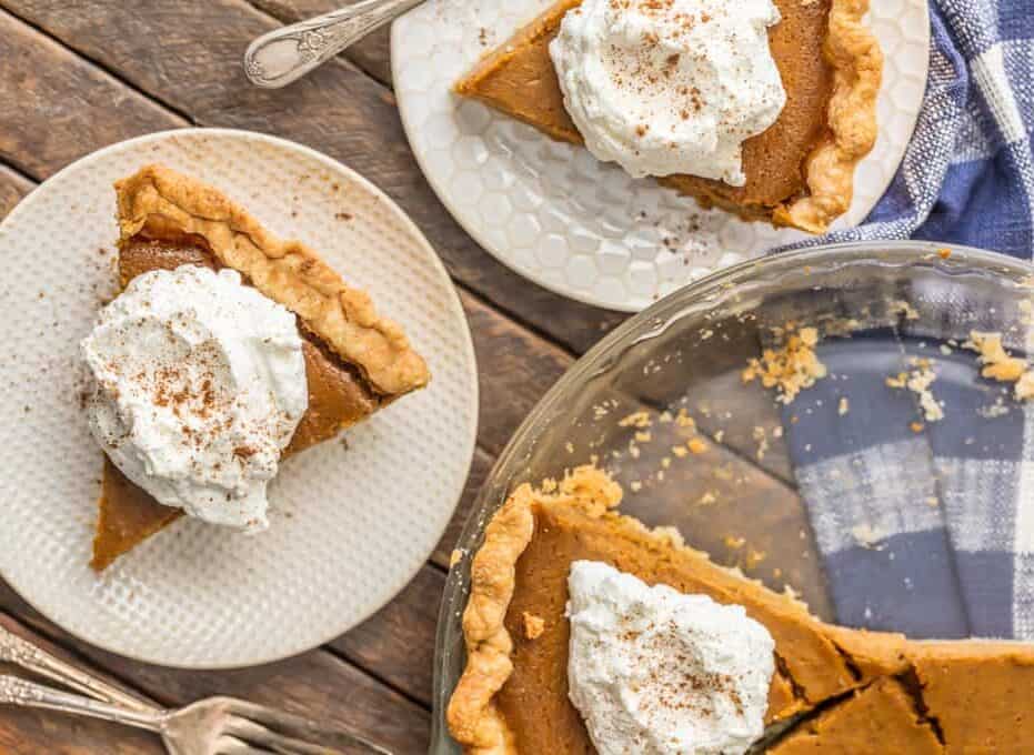 slices of pie topped with whipped cream on plates, next to a pie dish.