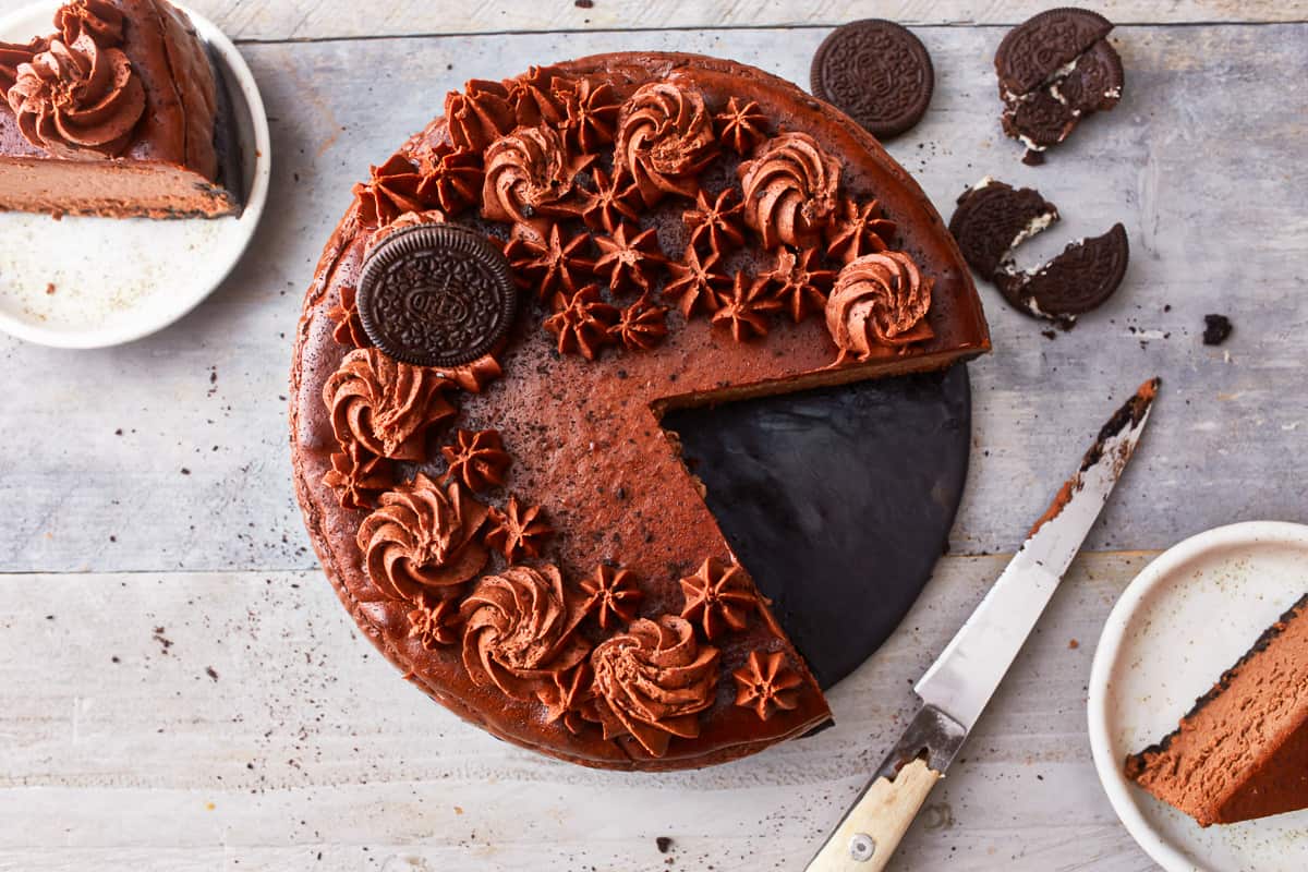 A chocolate oreo cheesecake with a slice taken out of it.