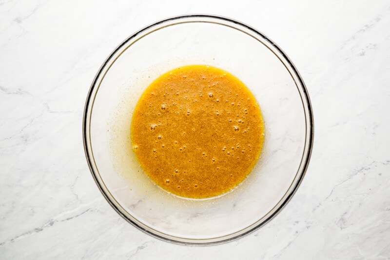 Orange sauce in a glass bowl on a marble surface.