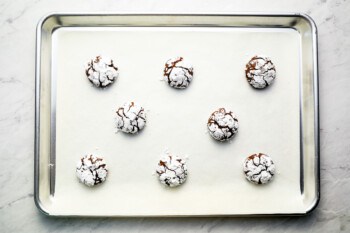 Chocolate crinkle cookies on a baking sheet.