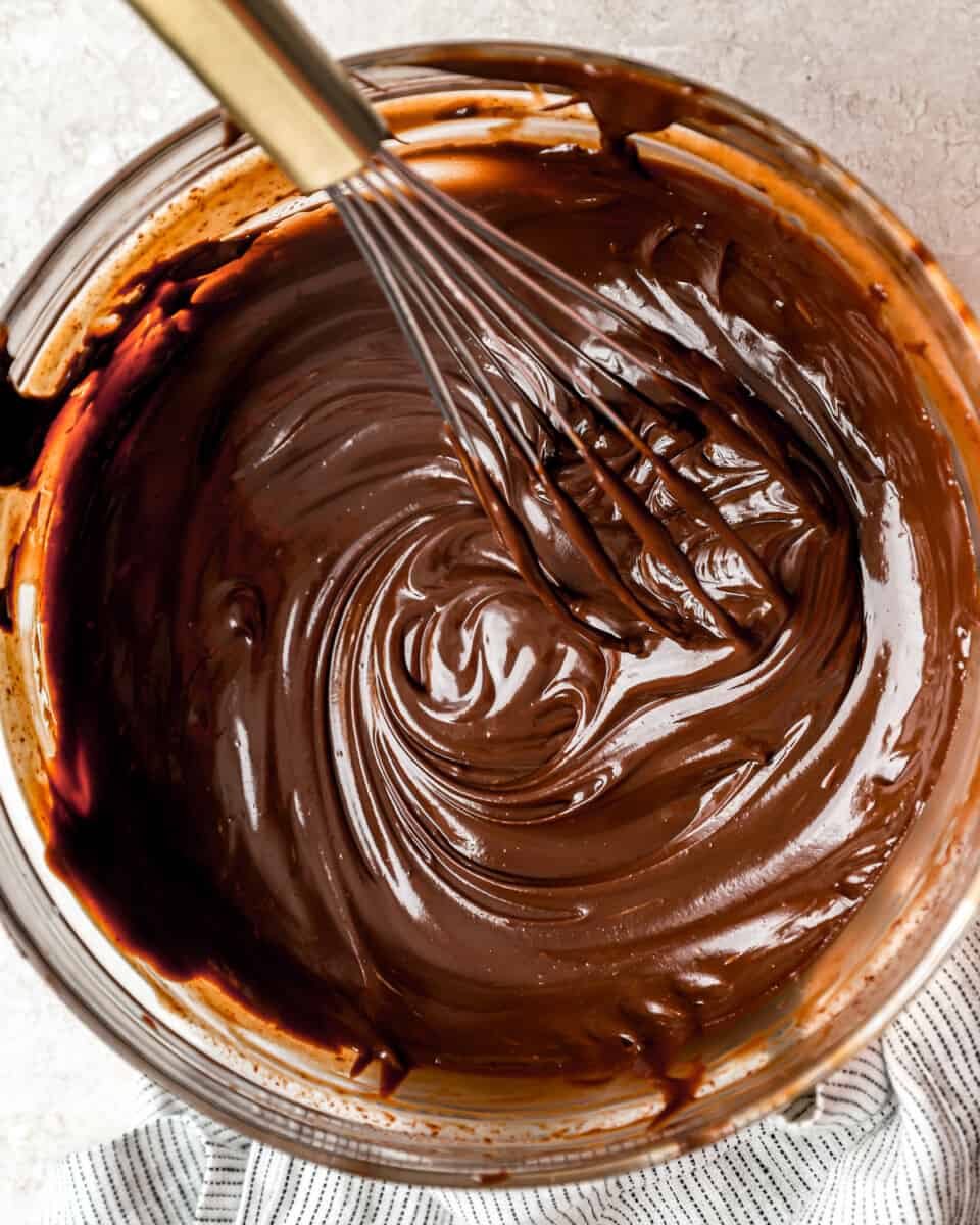 Chocolate ganache in a bowl with a whisk.