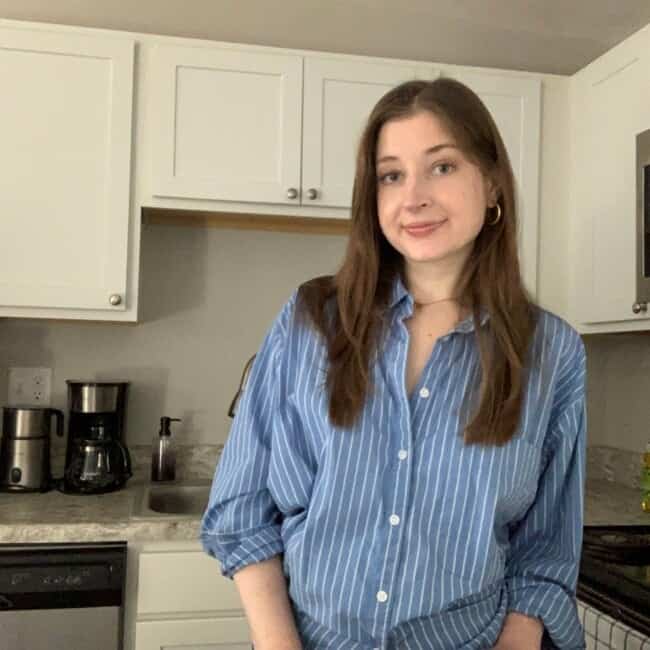 A food blogger in a blue shirt standing in a kitchen.