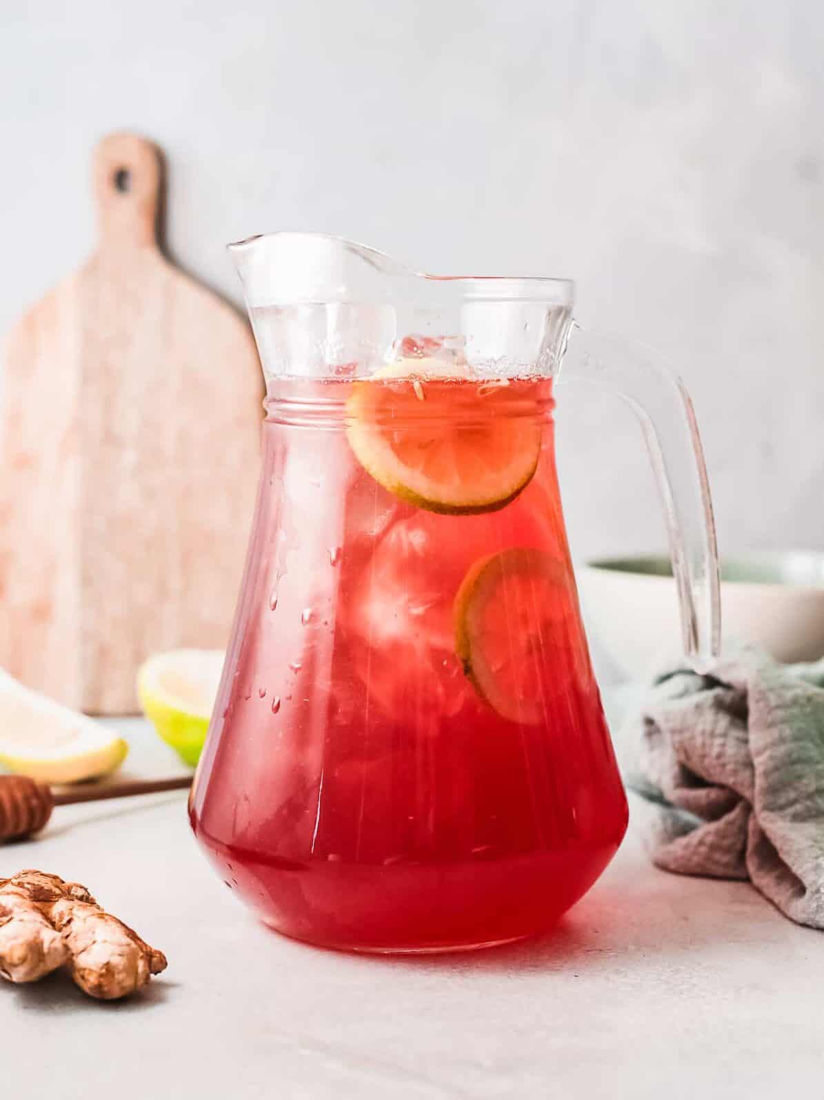 a red beverage in a pitcher with lemon slices and ice.