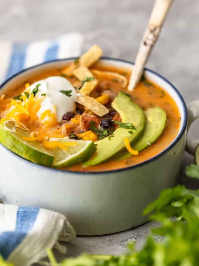 A bowl of tortilla soup topped with avocado, cheese, and sour cream