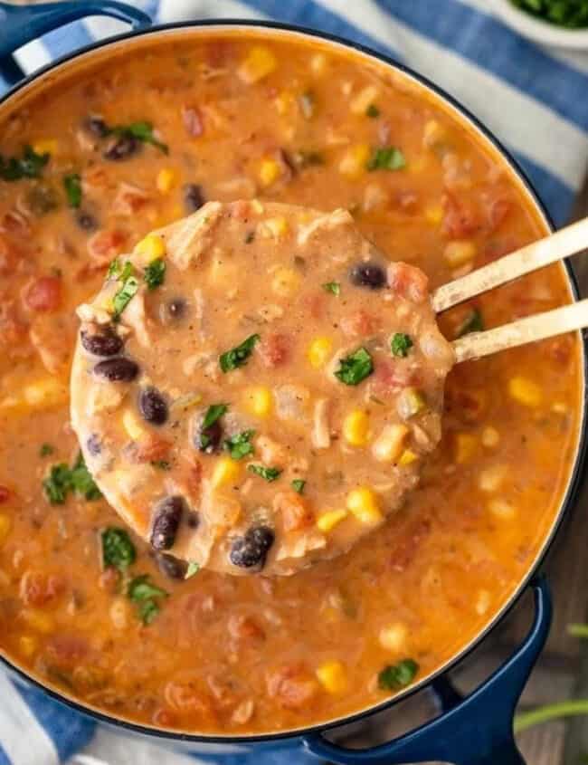 Creamy Mexican chicken tortilla soup in a pot with wooden spoons.