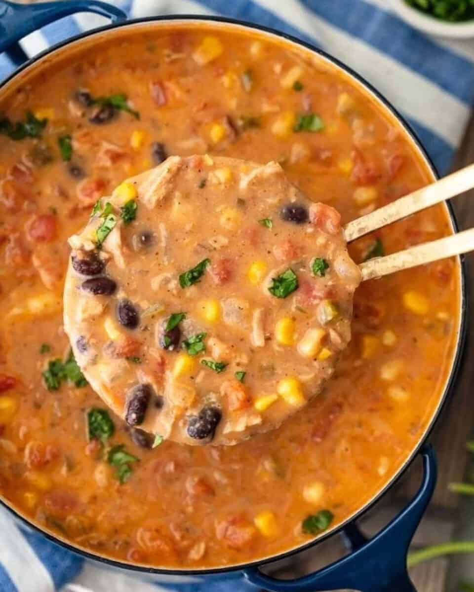 Creamy Mexican chicken tortilla soup in a pot with wooden spoons.