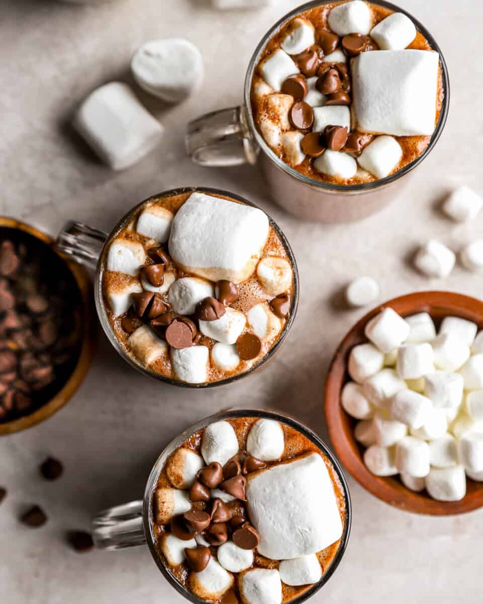 Mugs of hot chocolate with marshmallows and chocolate chips.