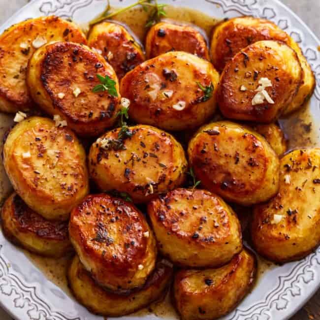 Roasted potatoes on a plate with herbs.