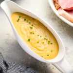 A bowl of mashed potatoes with gravy and ham.