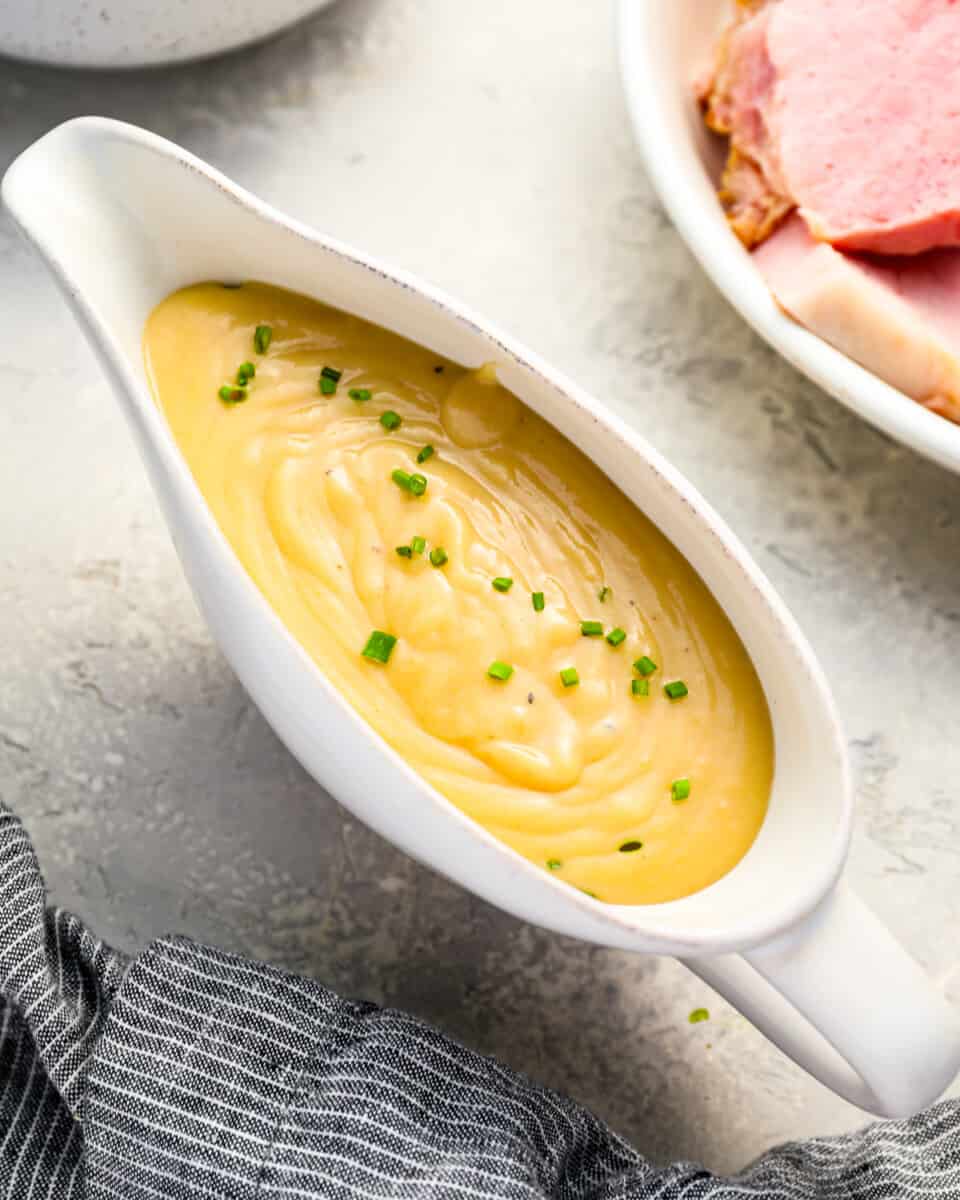 A bowl of ham gravy in a white porcelain have dish.