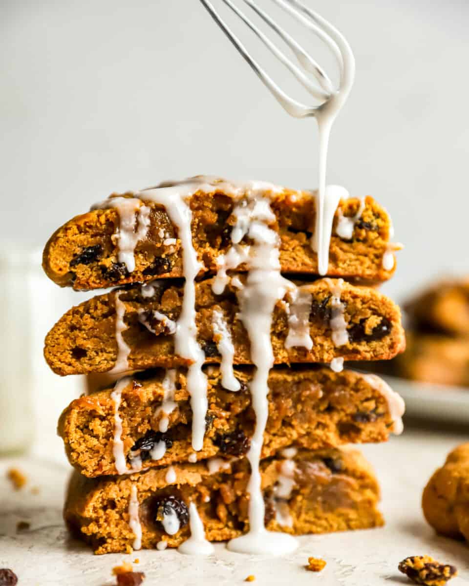 Drizzling white icing over a stack of hermit molasses bars.