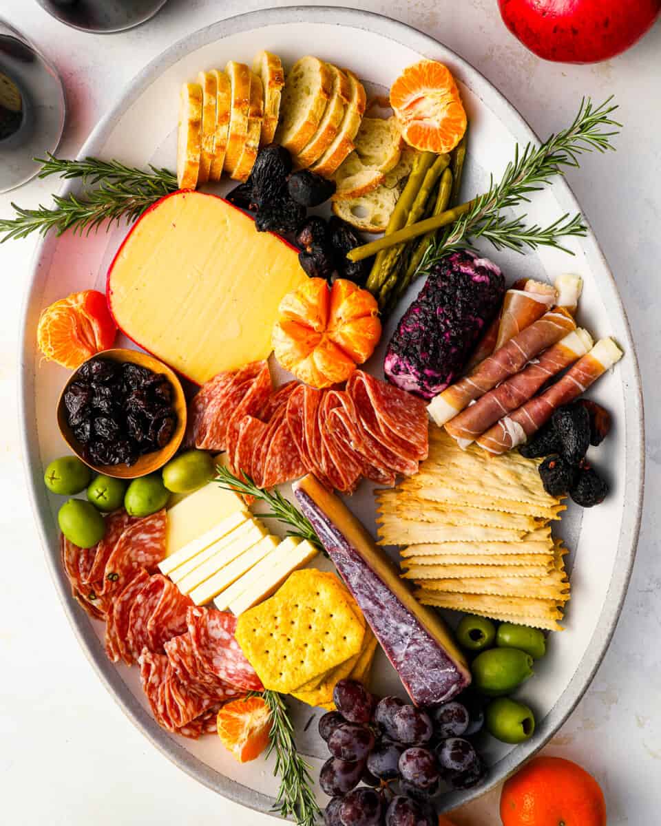 A holiday charcuterie board filled with meats, cheeses, fruits, olives, crackers, and more.