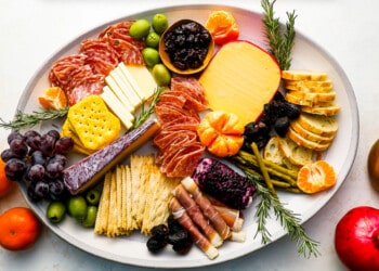 A plate with a variety of cheeses and fruits on it.