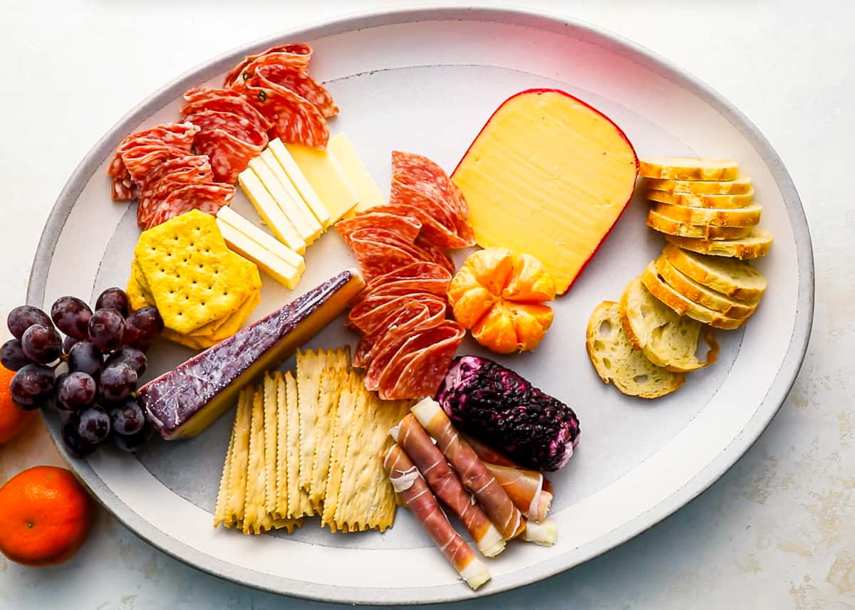 Cheese, meats, crackers, and fruit on a cheese board.