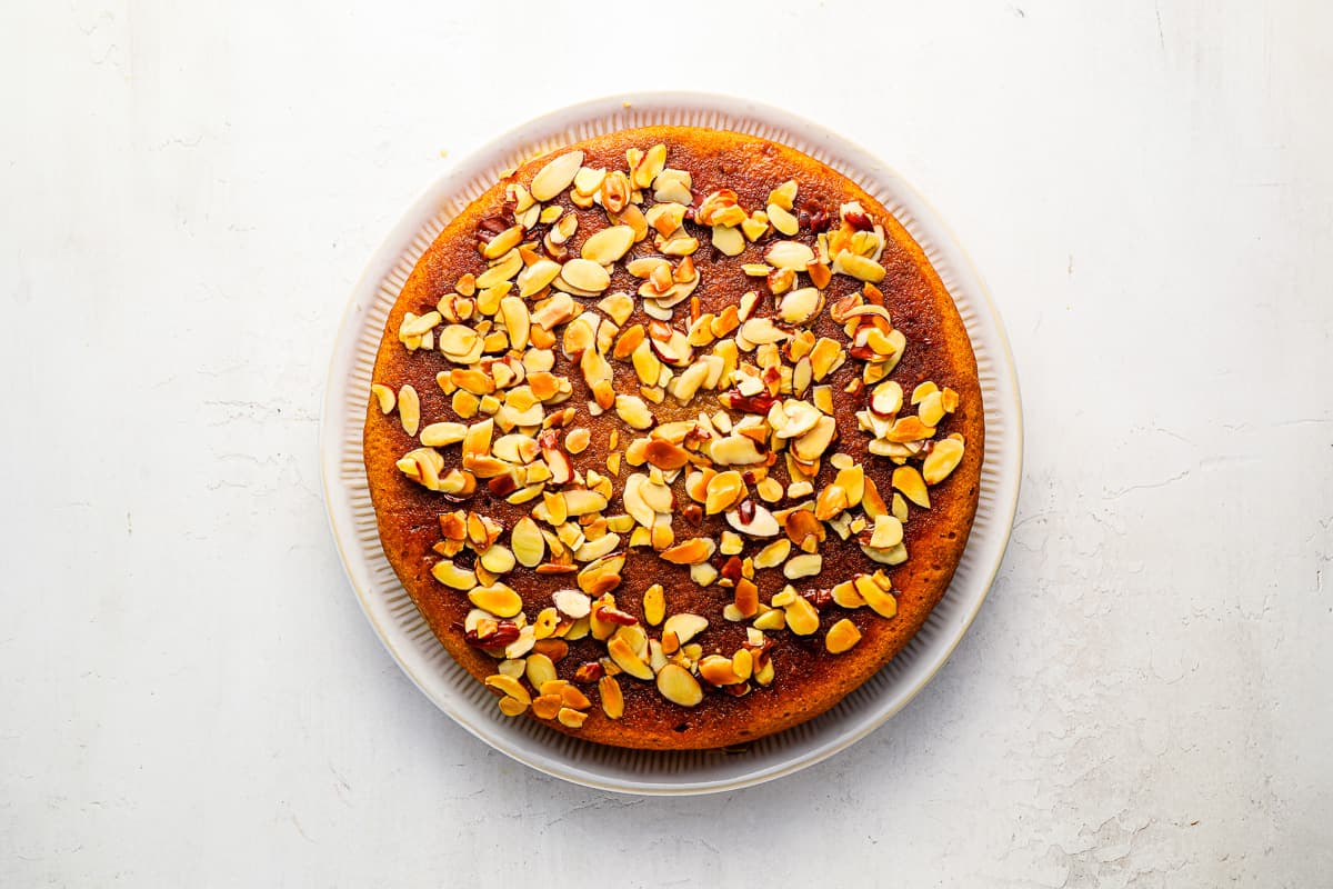 A round honey cake topped with sliced almonds.