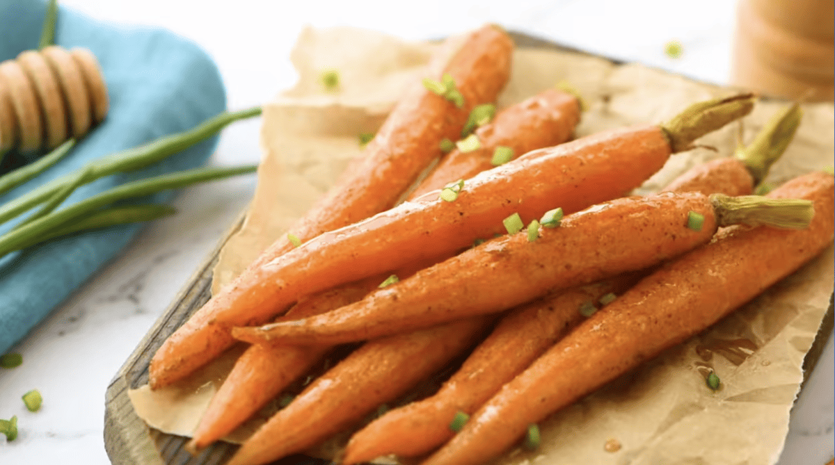 honey glazed carrots on parchment paper topped with chives.