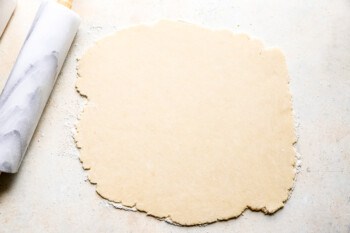 A rolling pin next to a piece of dough.