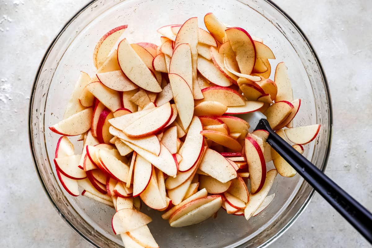 Sliced apples in a bowl with a knife.