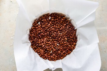 Brown beans in a paper bag on a table.