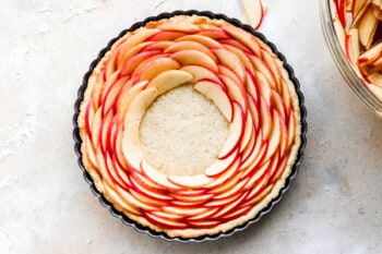 An apple tart in a pan with a slice of apple on top.