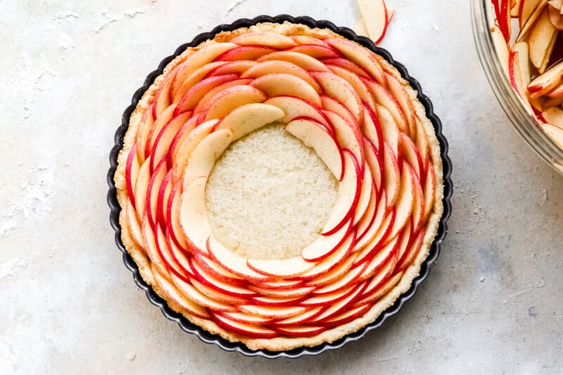 An apple tart in a pan with a slice of apple on top.