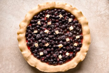 A blueberry pie in a pie crust on a table.