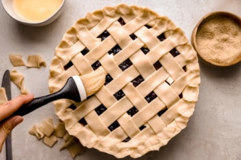 A person is slicing a pie with a lattice pattern.