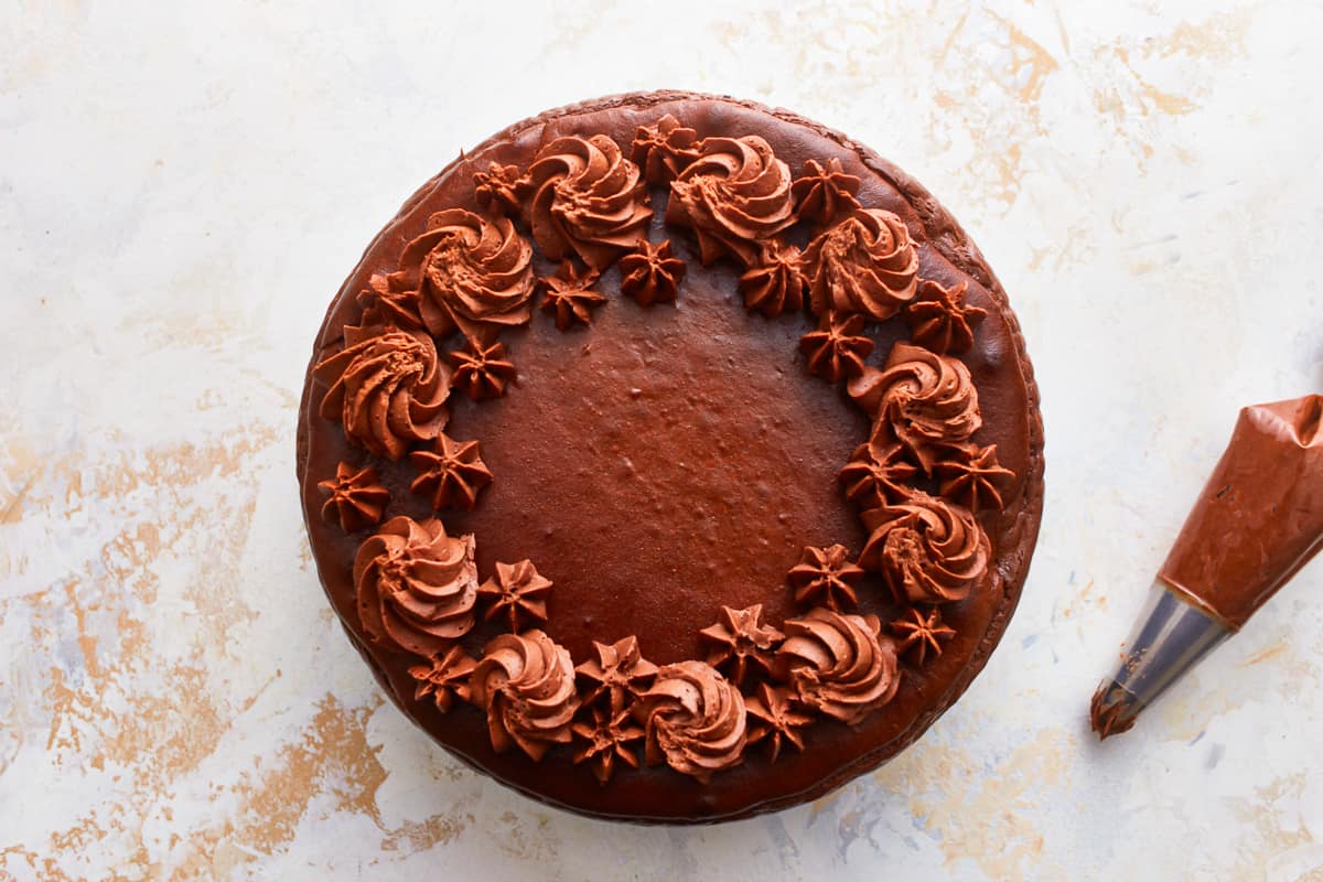 Chocolate cheesecake decorated with whipped frosting swirls.