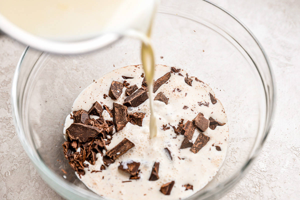 Cream poured over chopped chocolate in a bowl.