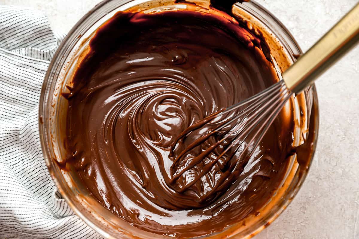 Chocolate ganache in a bowl with a whisk.