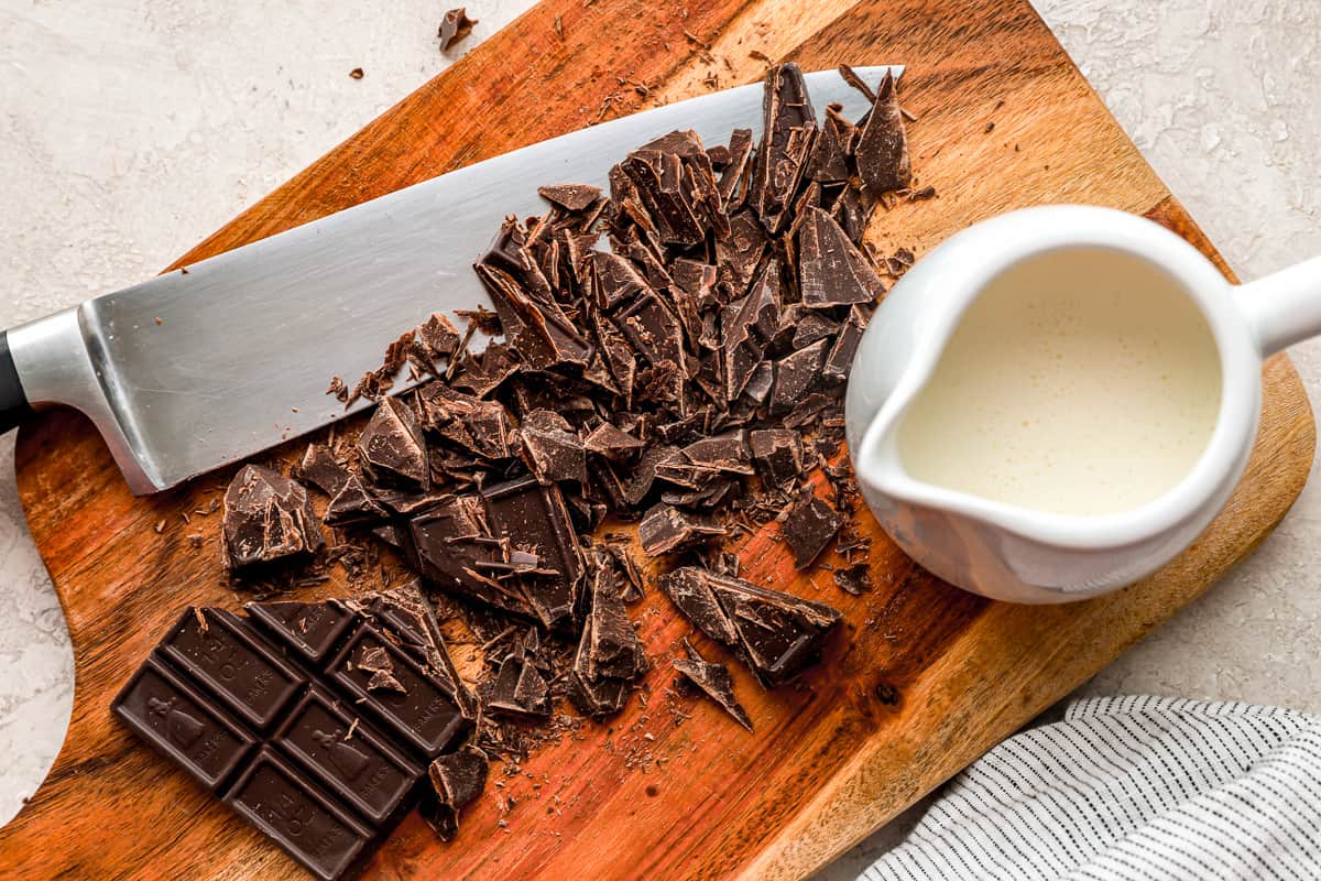 Chopped chocolate and cream on a cutting board.