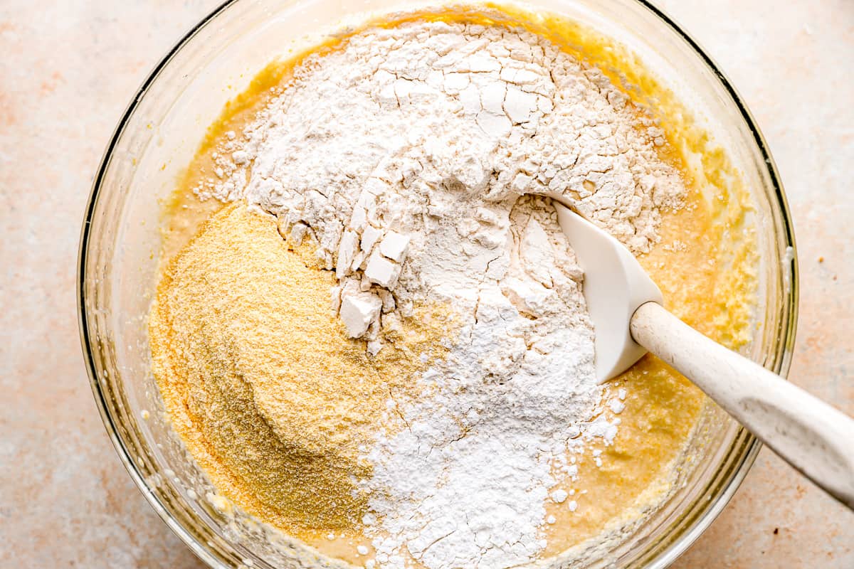 Mixing flour, cornmeal, and baking powder into batter.
