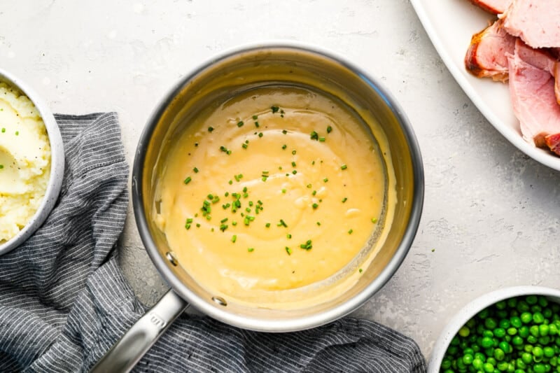 Ham, peas, potatoes and gravy on a table.