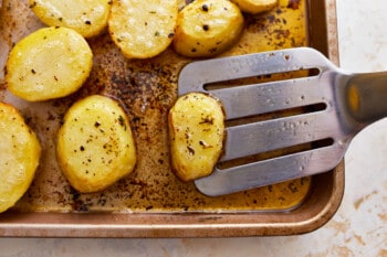 Roasted potatoes on a baking sheet with a spatula.