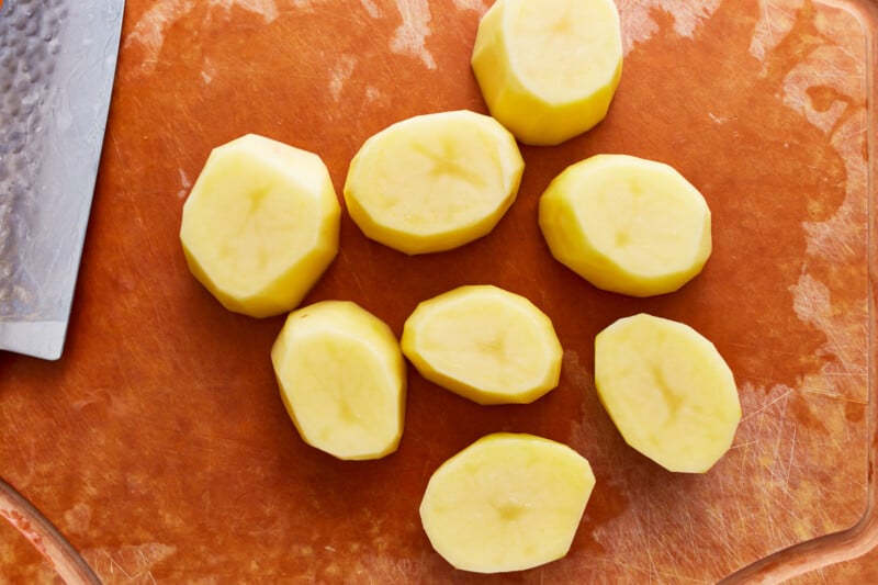 Sliced potatoes on a cutting board with a knife.