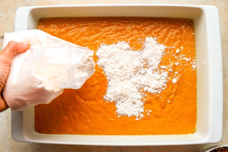 A person pouring flour into a baking dish.