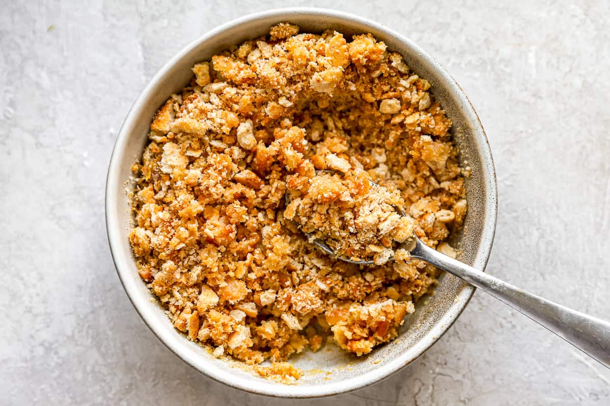 Breadcrumb and cracker mixture in a bowl with a spoon.