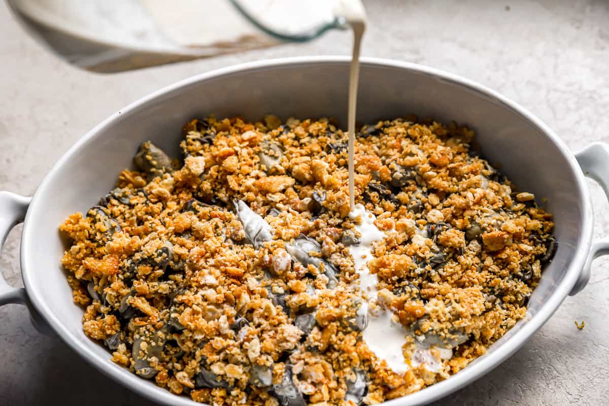 Pouring a creamy liquid into a casserole.