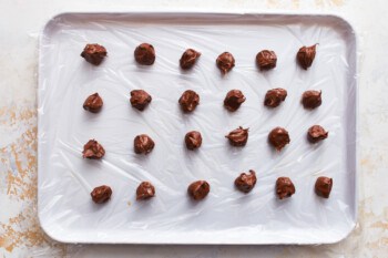 Balls of nutella lined up on a baking tray.
