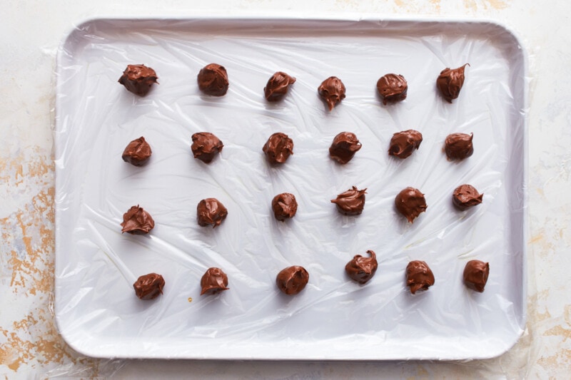 Balls of nutella lined up on a baking tray.