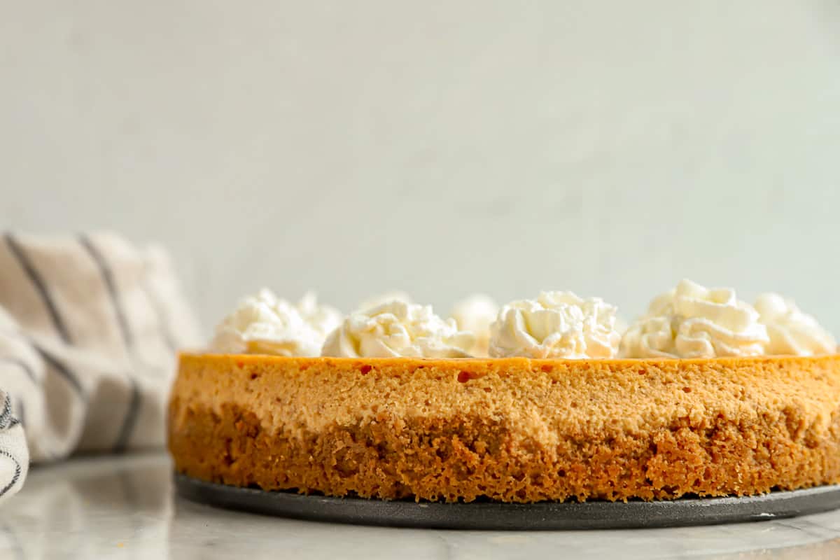 A sweet potato cheesecake on a plate with whipped cream.