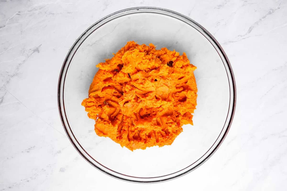 overhead view of mashed sweet potato in a glass bowl.