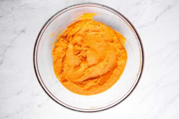 overhead view of mashed sweet potato and egg in a glass bowl.