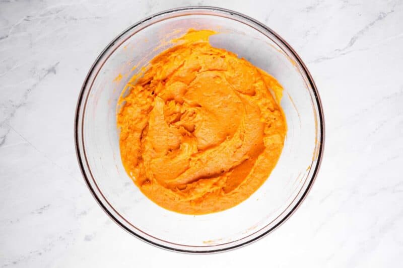 overhead view of mashed sweet potato and egg in a glass bowl.