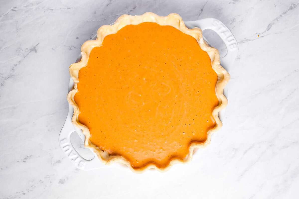 overhead view of sweet potato pie filling poured into crust in a pie pan.