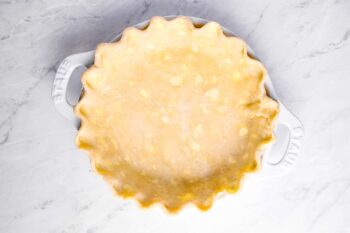 overhead view of sweet potato pie crust pressed into a pie pan and crimped.