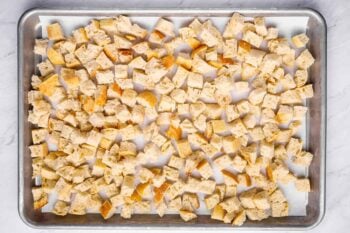 overhead view of cubes of bread on a baking sheet.