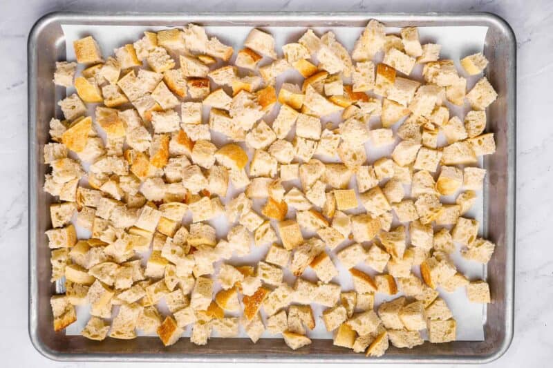 overhead view of cubes of bread on a baking sheet.