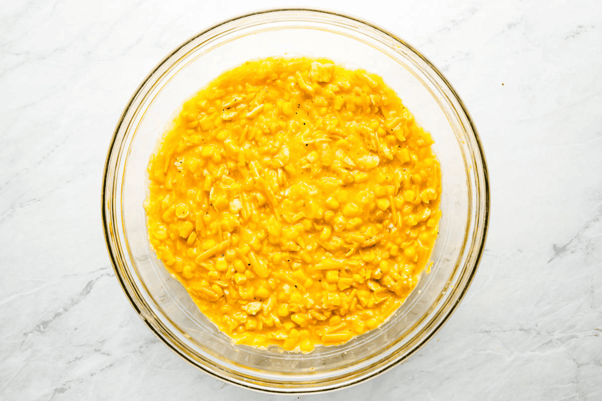Scalloped corn casserole mixture in a glass bowl. 